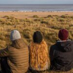 3 people sitting on the beach