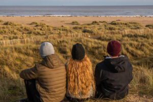 3 people sitting on the beach