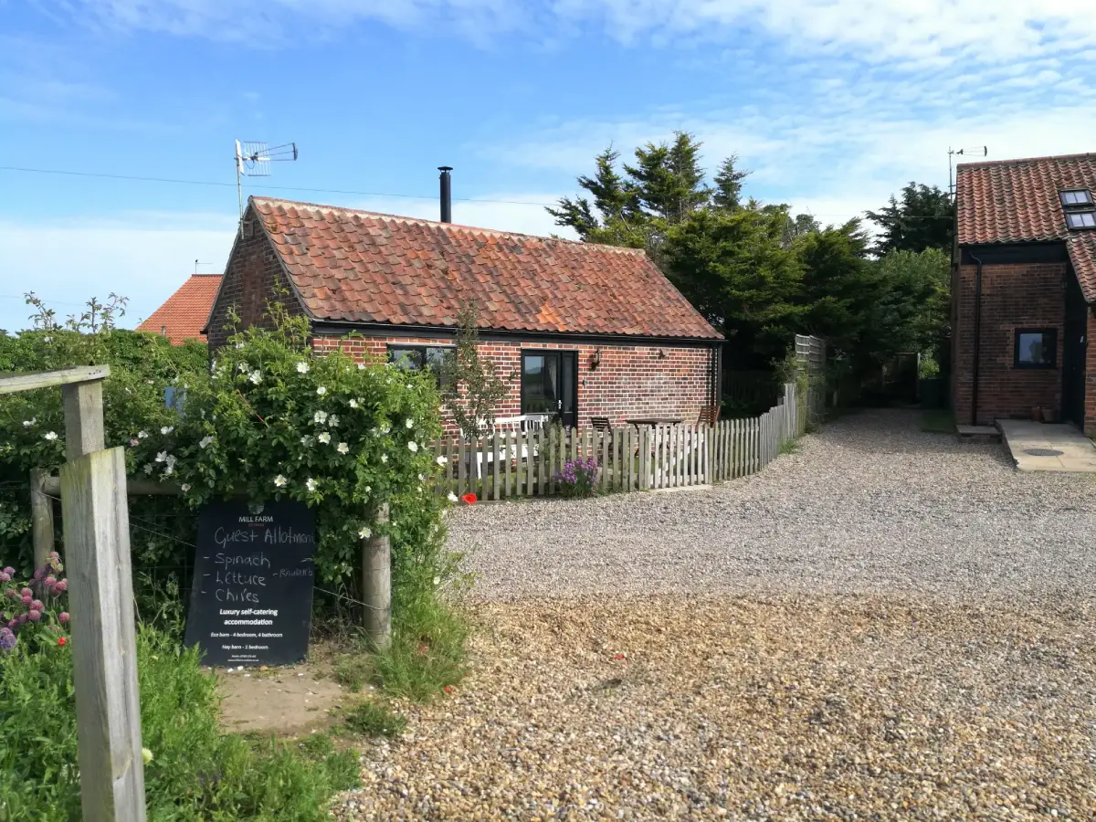 Chalkboard sign and red‑brick cottages framed naturally under blue sky