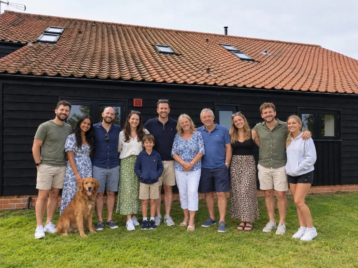 A large family group and their golden retriever dog standing outside the luxury self-catering holiday barns in Norfolk.